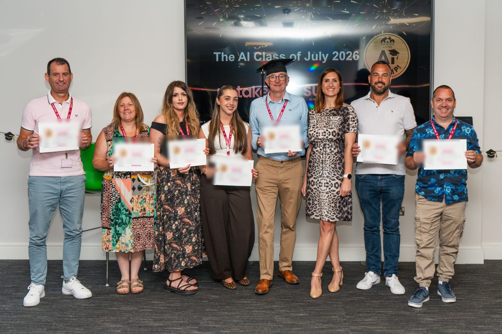 Colleagues from Magenta Living holding SUSY certificates at their graduation event, in front of a screen reading The AI Class of July 2026